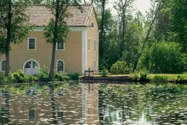Ein gelbes Gebäude, das sich in einem Seerosenteich in Eriksberg spiegelt.