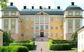 Die Hauptfassade von Eriksbergs slott mit Seitenflügeln und Kiesweg.