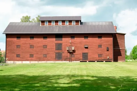 Stort falurött magasin i trä med rader av luckor står på grön gräsmatta vid Eriksbergs slott.