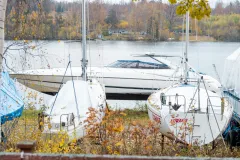 Asfaltväg genom gröna åkrar med gårdar i bakgrunden.
