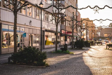 Cobbled pedestrian street lined with shop fronts and Christmas garlands with stars.
