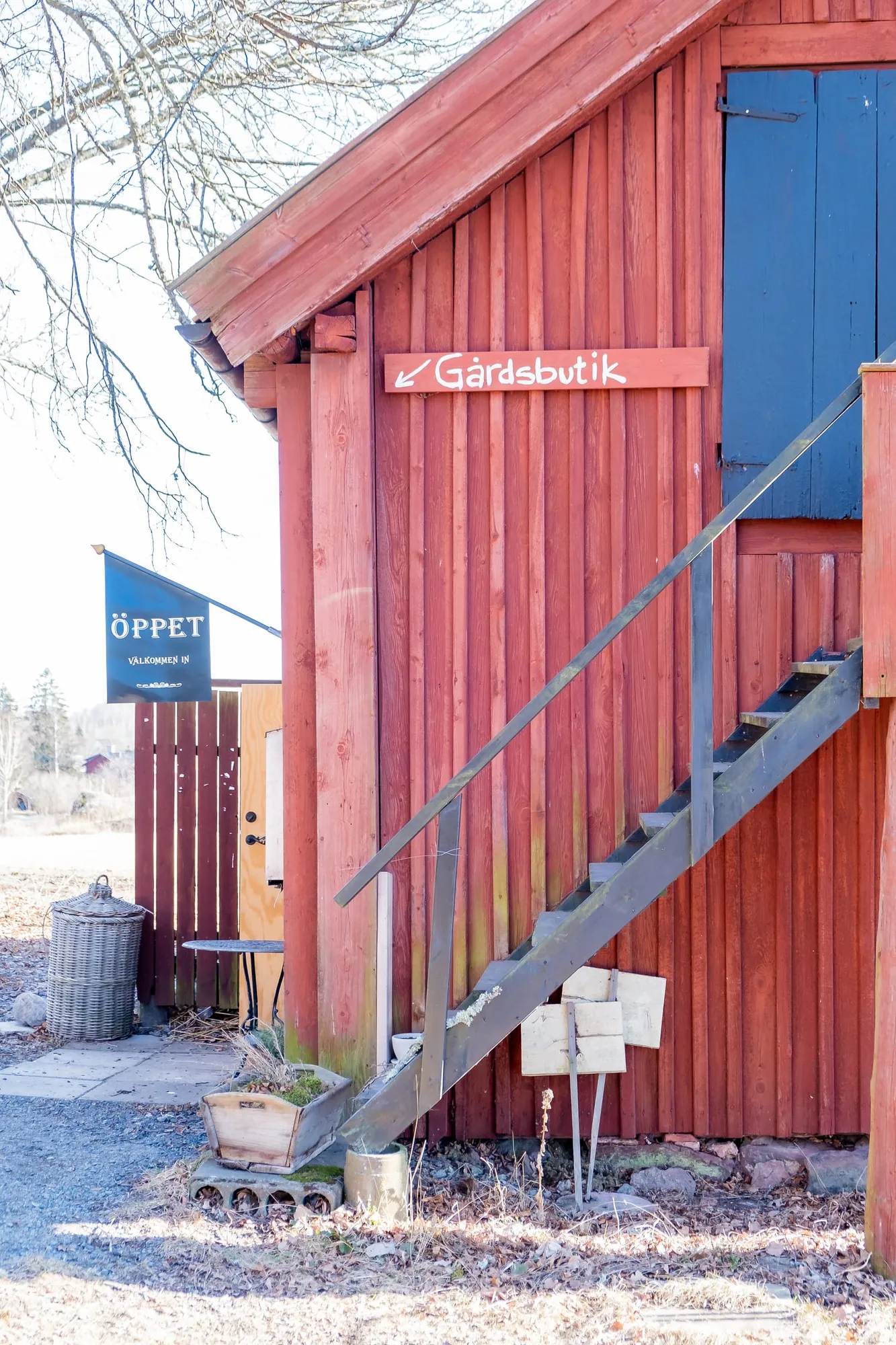 Rotes Holzgebäude mit Außentreppe und Schildern zum Hofladen bei Fridhems kaffestuga.